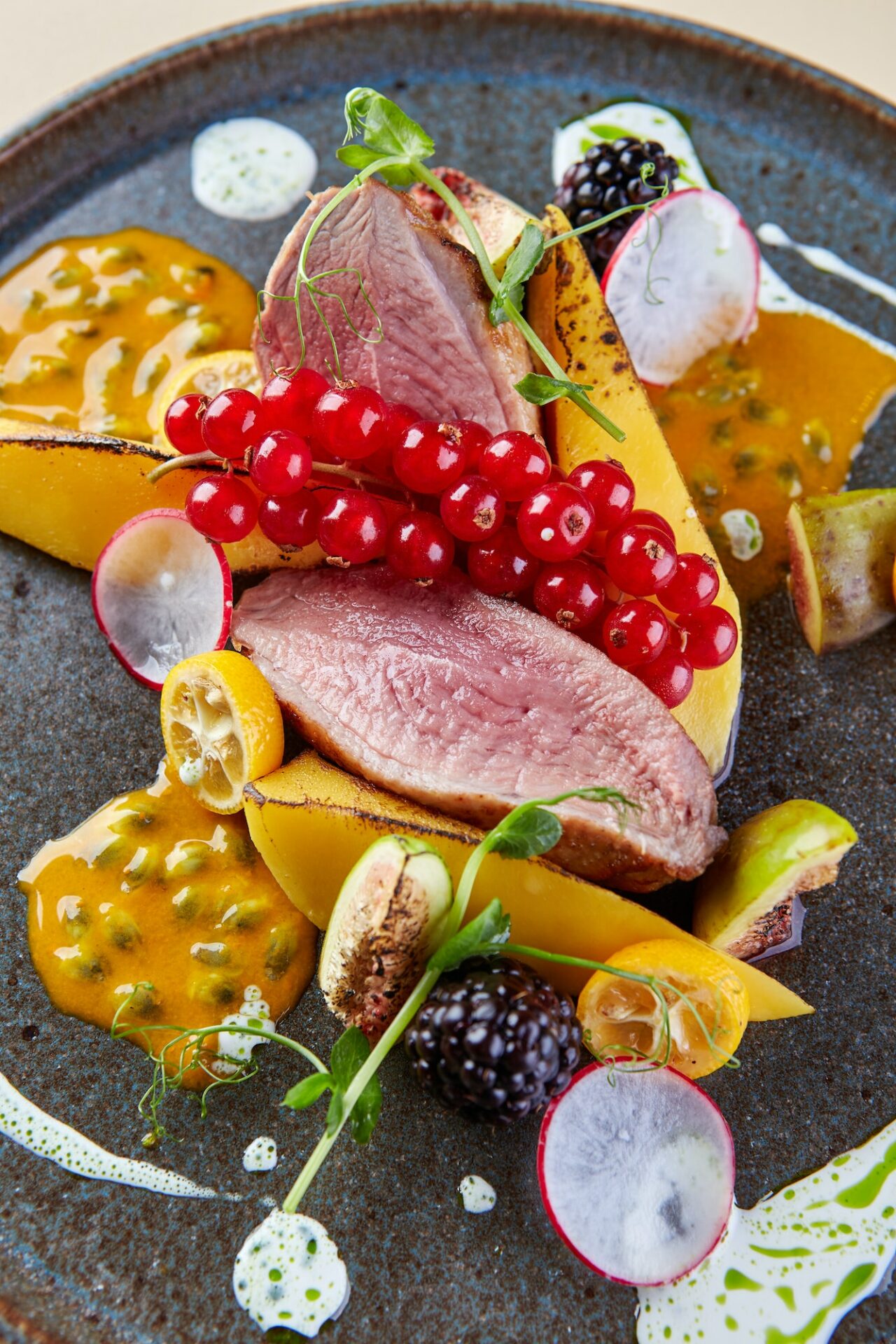 Beautiful restaurant dish of meat with vegetables, tropical fruit sauce and garnished with berries